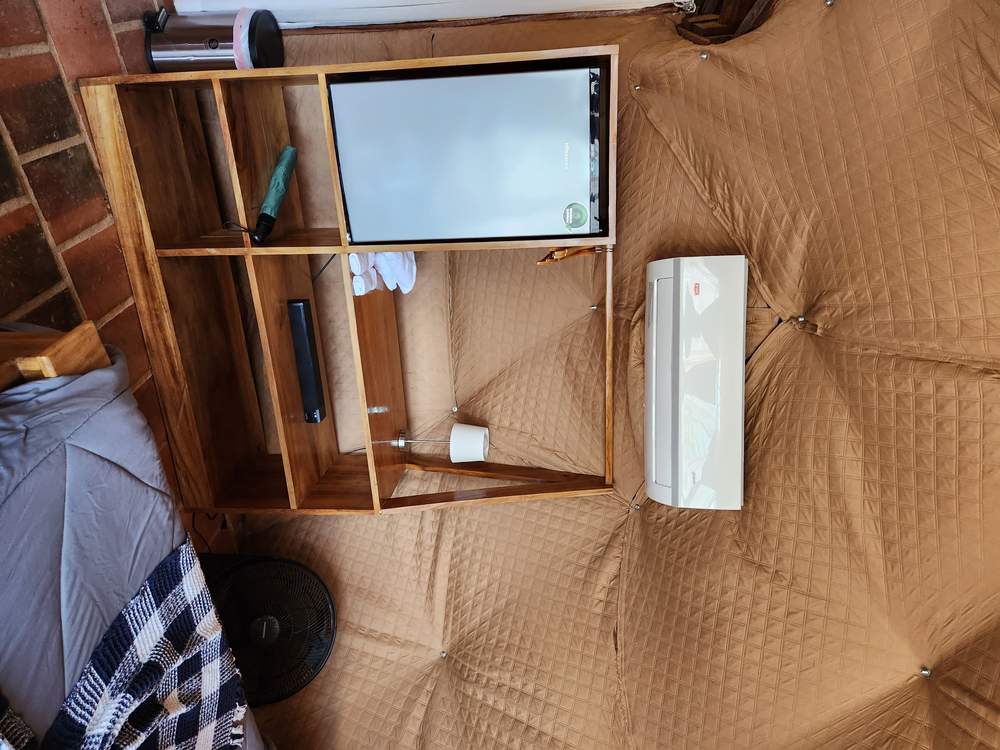 Rincón del domo con mini refrigeradora, aire acondicionado, toallas enrolladas y repisas de madera